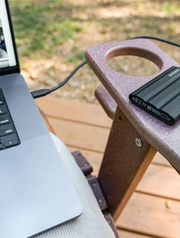 Laptop, external hard drive, and mug on chair